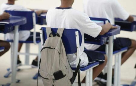 Aluno sentado em carteira escolar.