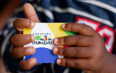 Crian&ccedil;a segurando cart&atilde;o do Bolsa Fam&iacute;lia.