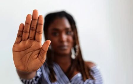 Imagem de uma mulher com a palma da m&atilde;o aberta, ilustrando a tentativa de parar com o racismo.