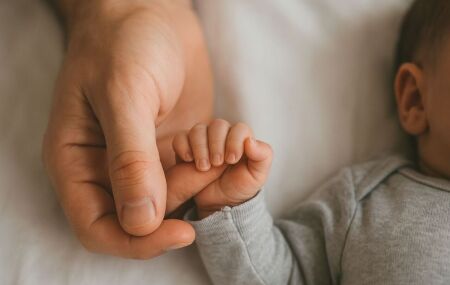 Beb&ecirc; segurando m&atilde;o do pai. 