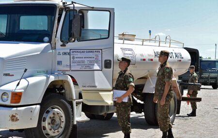 Carro-pipa do Ex&eacute;rcito e soldados ao lado.