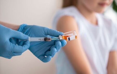 Profissional de sa&uacute;de aplica vacina em crian&ccedil;a para prevenir meningite, principal medida de prote&ccedil;&atilde;o.