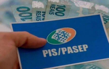 Pessoa segurando cart&atilde;o do PIS/Pasep e dinheiro do abono salarial.