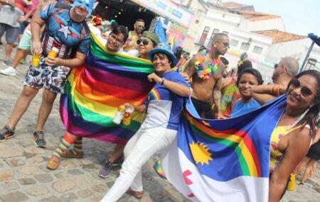 Recifenses segurando uma bandeira LGBTQUIA+ e a bendeira de Pernambuco.