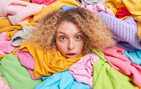 Mulher analisa diferentes pe&ccedil;as coloridas enquanto escolhe o tom ideal para usar na virada do ano.