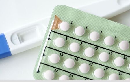 Cartela de comprimidos ao lado de um teste de gravidez, imagem que reflete casos de gesta&ccedil;&atilde;o durante o uso de medicamentos de emagrecimento.