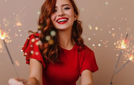 Mulher veste vermelho e segura fa&iacute;scas festivas, simbolizando a energia e o entusiasmo de novos come&ccedil;os.