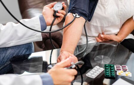 Profissional de sa&uacute;de acompanha a press&atilde;o arterial de um paciente para refor&ccedil;ar a preven&ccedil;&atilde;o do AVC.