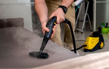 T&eacute;cnico aplica produto impermeabilizante em sof&aacute; em ambiente residencial, garantindo prote&ccedil;&atilde;o contra l&iacute;quidos e sujeira.