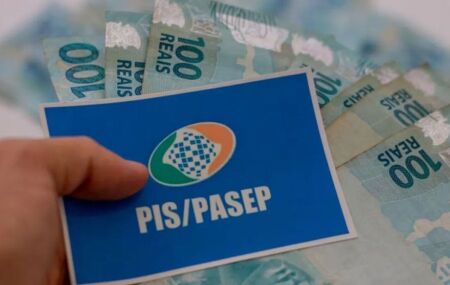 Pessoa segurando cart&atilde;o do PIS/Pasep com dinheiro do abono.