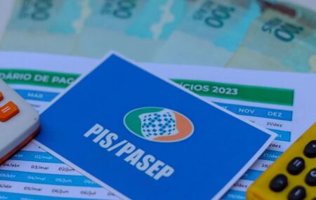 Cart&atilde;o do PIS/Pasep ao lado de dinheiro do abono e calculadoras.