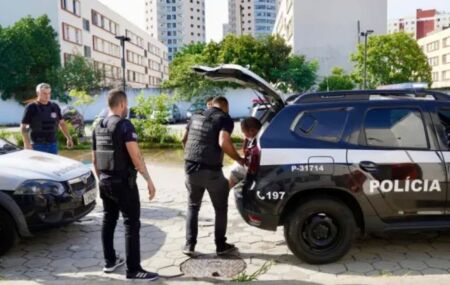 Policiais civis tirando homem de viatura.