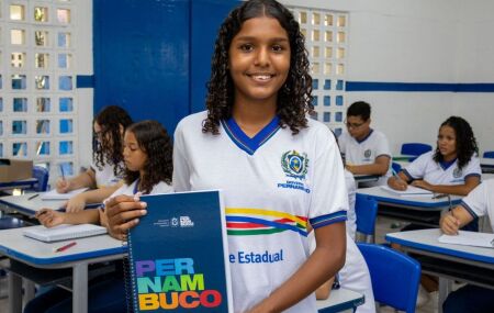 Estudante da Rede Estadaul de Ensino de Pernambuco segurando um caderno com a logo do Governo de Pernambuco.