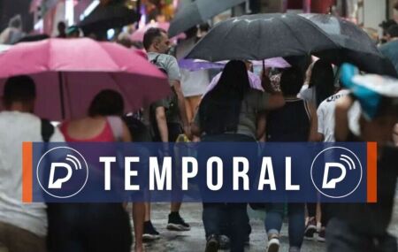 Pessoas se abrigando das precipita&ccedil;&otilde;es com guarda-chuvas.