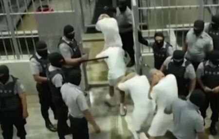 Detentos sendo conduzidos &agrave;s celas por policiais.