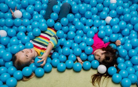 Duas crian&ccedil;as brincam na piscina de bolinhas em espa&ccedil;o kids de restaurante.