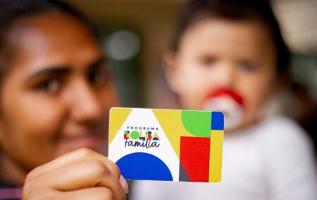 M&atilde;e com beb&ecirc; segurando cart&atilde;o do Bolsa Fam&iacute;lia.