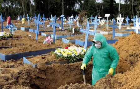 Coveiro com roupa de prote&ccedil;&atilde;o em cemit&eacute;rio, durante per&iacute;odo de pandemia, no Brasil.