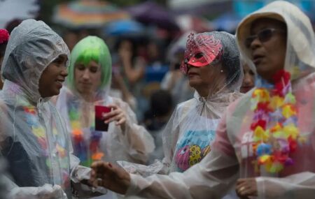 Pessoas brincando Carnaval na chuva.