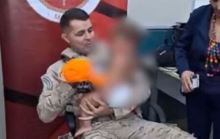 Pol&iacute;cial com crian&ccedil;a no bra&ccedil;o.