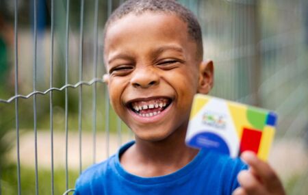 Crian&ccedil;a segurando cart&atilde;o do Bolsa Fam&iacute;lia.