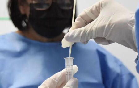 Cientistas com frasco para analisar Covid-19.