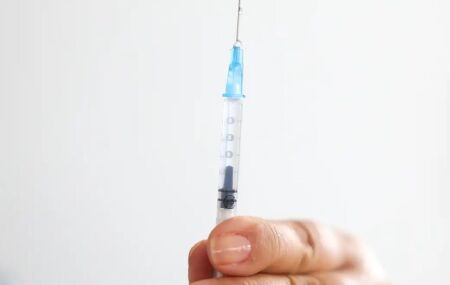 Pessoa com seringa de vacina contra HPV em m&atilde;os.