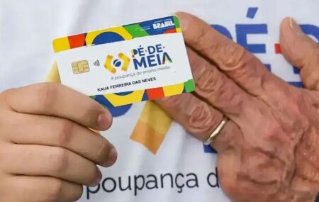 Pessoa segurando cart&atilde;o do P&eacute;-de-Meia ao lado da m&atilde;o de Lula.