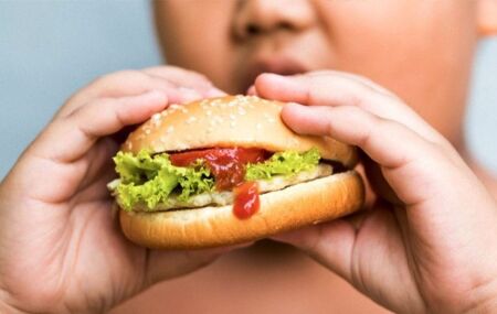 Crian&ccedil;a comendo hamburguer.