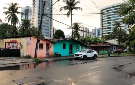 As casas que a prefeitura quer remover constrastam com os pr&eacute;dios ao redor  