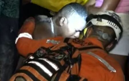Esposo e pai das v&iacute;timas sendo consolado por um bombeiro.