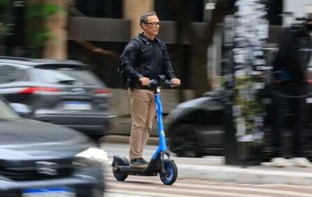 Homem em cima de patinete el&eacute;trico.