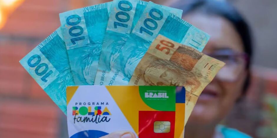 Senhora segurando cart&atilde;o do Bolsa Fam&iacute;lia e dinheiro do benef&iacute;cio.