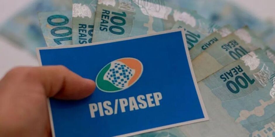 Pessoa segurando cart&atilde;o do PIS/Pasep com dinheiro do abono.