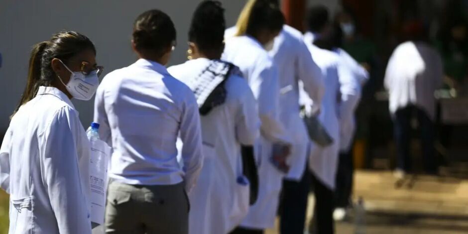Pessoas com jaleco m&eacute;dico em fila.
