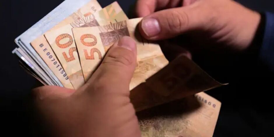 Pessoa contanto notas de dinheiro.