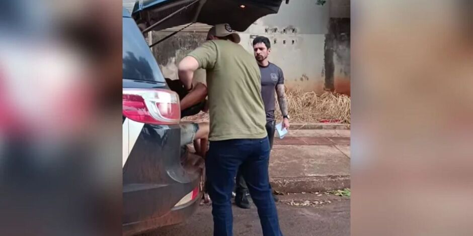 Momento em que suspeitos s&atilde;o colocados na viatura.