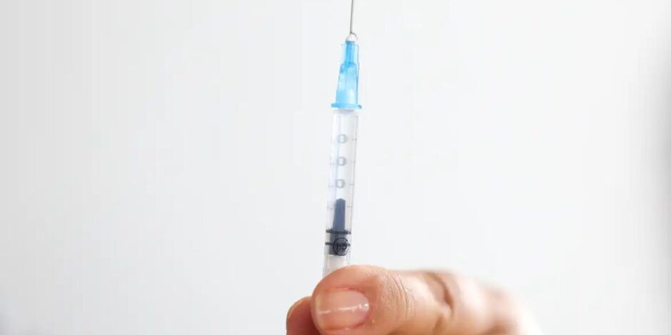 Pessoa com seringa de vacina contra HPV em m&atilde;os.