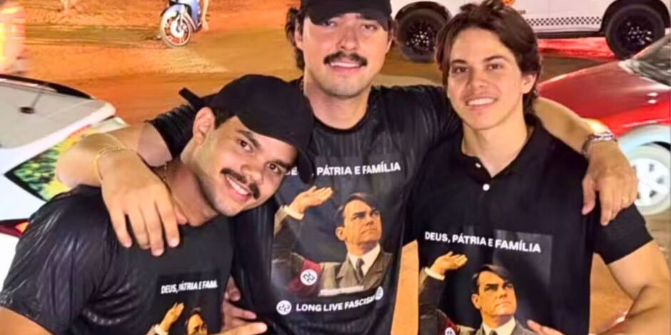 Nas imagens divulgadas, eles aparecem com camisetas pretas contendo refer&ecirc;ncias a Adolf Hitler.