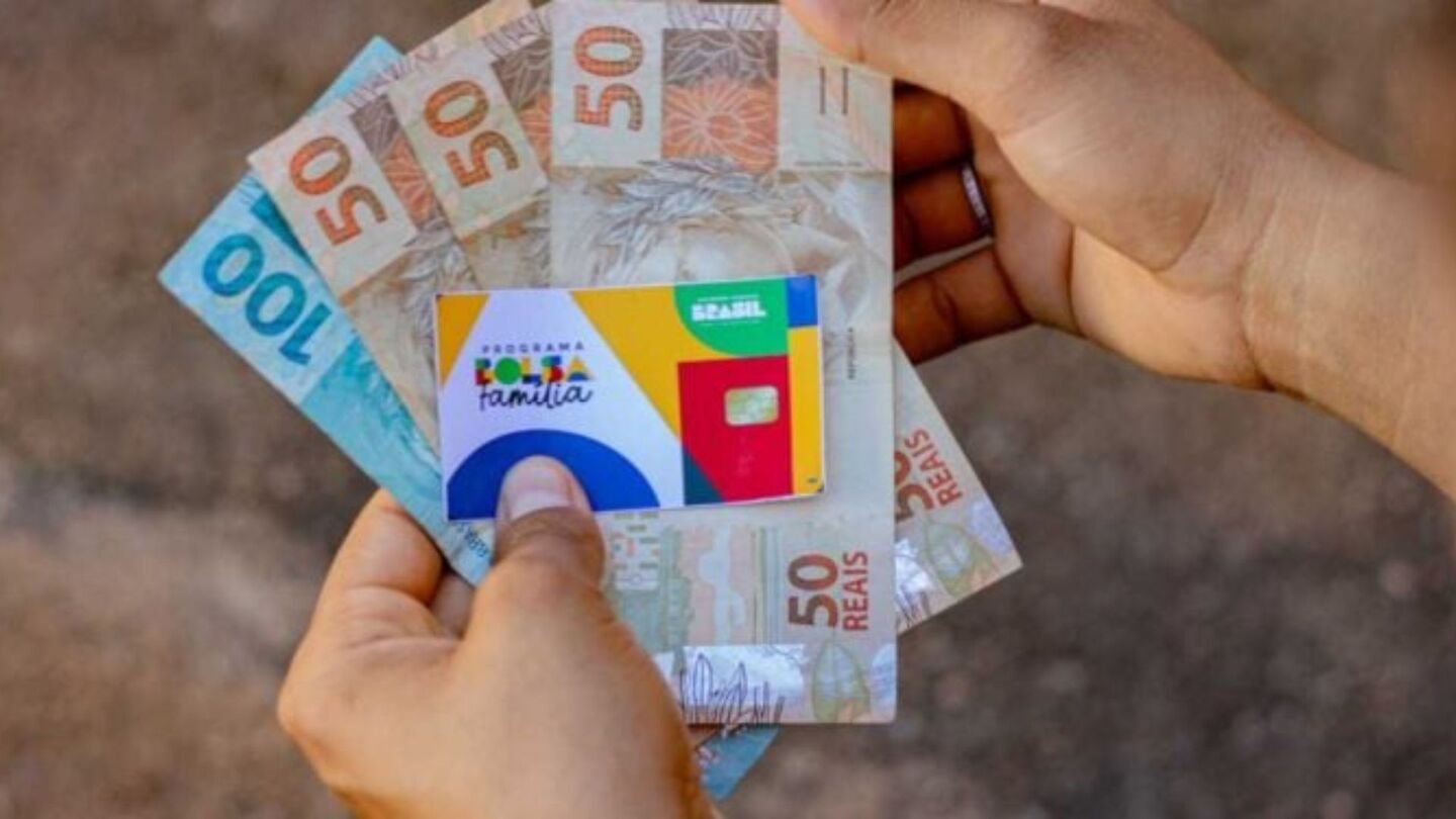 Pessoa segurando cartão do Bolsa Família e benefício.