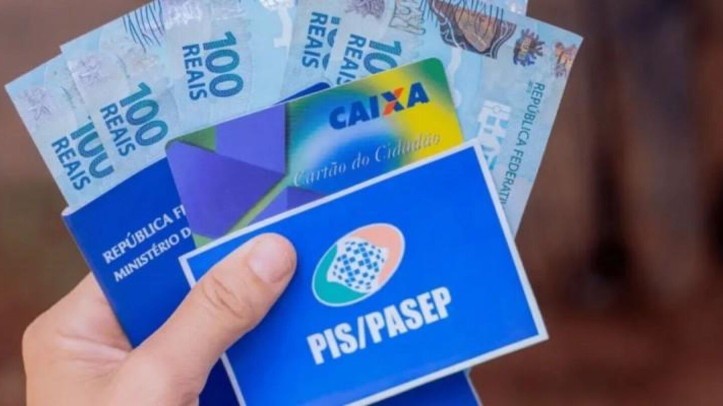 Pessoa segurando cartão do PIS/Pasep, da Caixa e dinheiro do benefício.