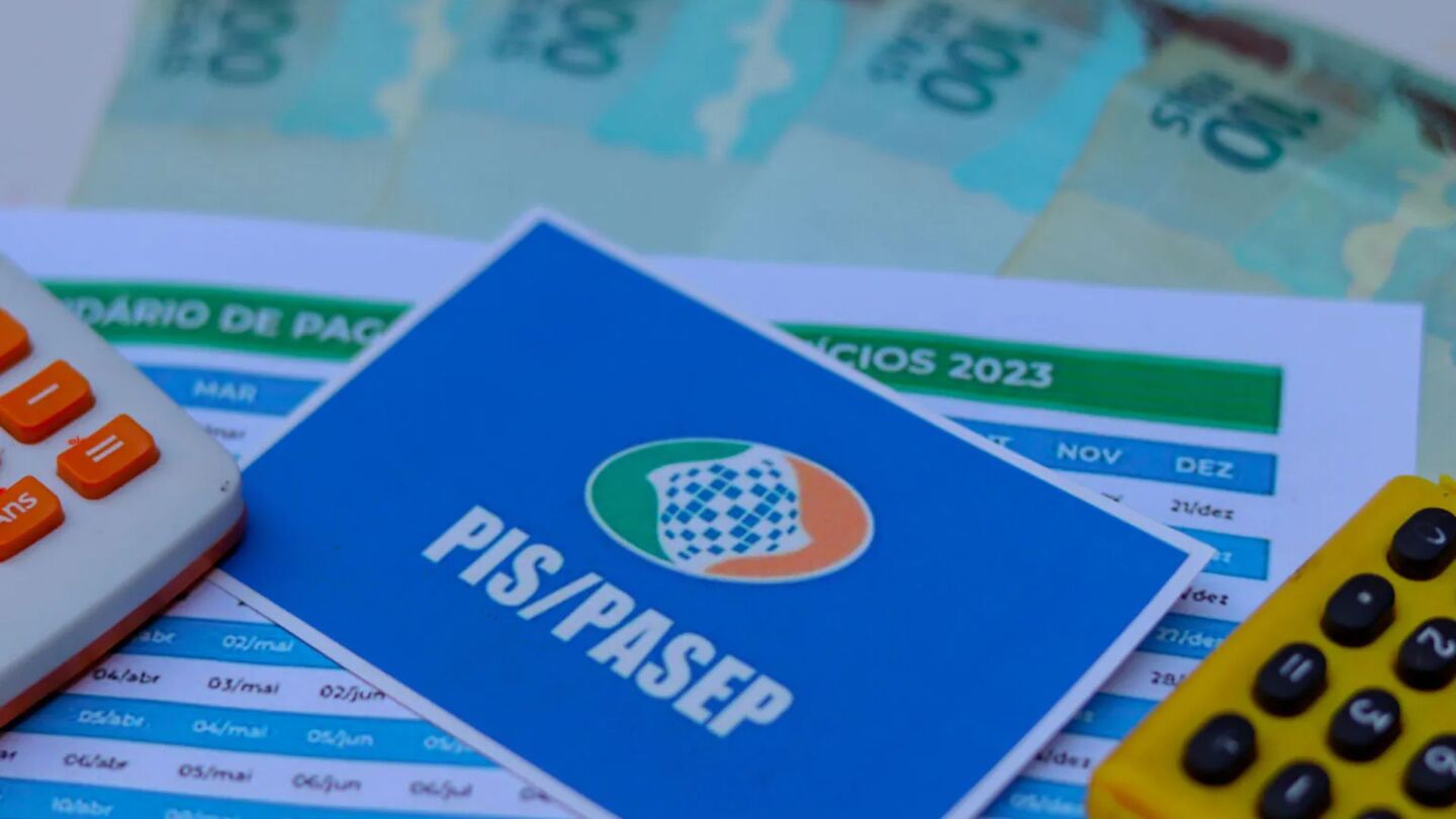 Cartão do PIS/Pasep ao lado de dinheiro do abono e calculadoras.