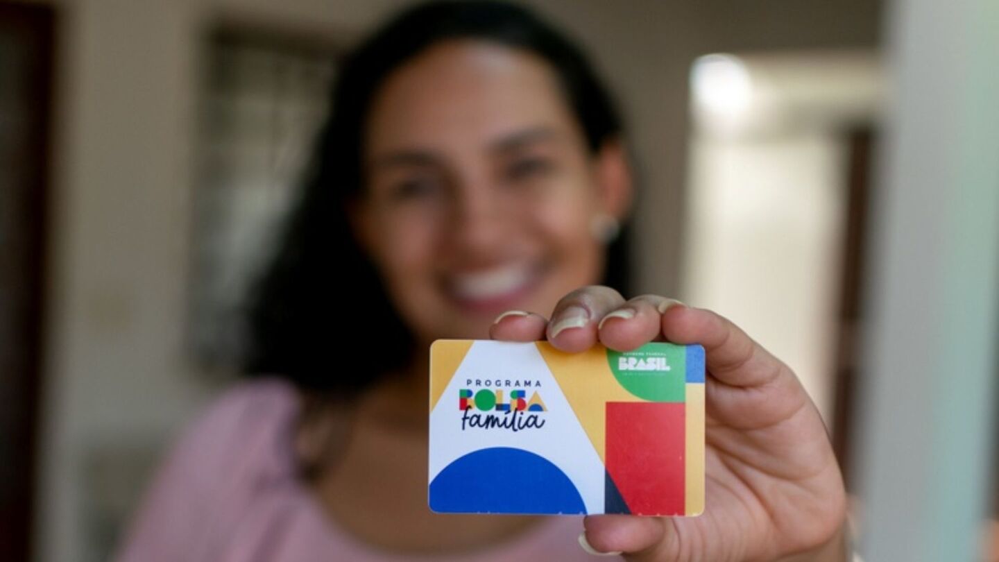 Mulher segurando cartão do Bolsa Família.